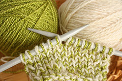 knitting needles with green and cream yarn
