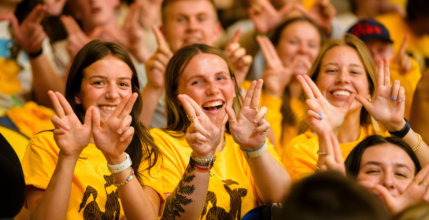 A group of students hold up a “W” with their hands at a UW event.