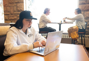 A UW student works on their computer at a campus cafe.