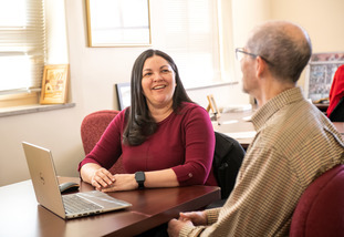 Two UW staff faculty members share a laugh as they work together at a table.