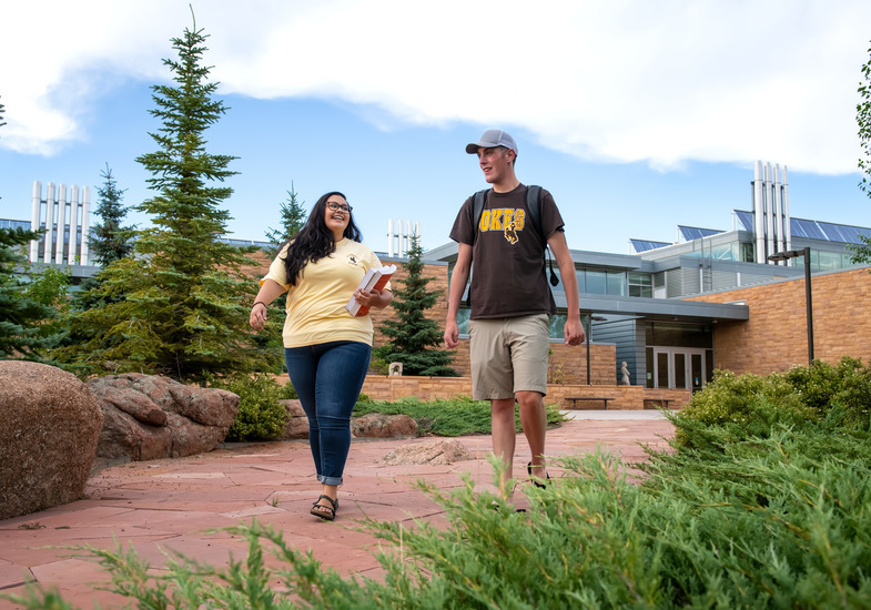 two student walk in front of the visual arts building