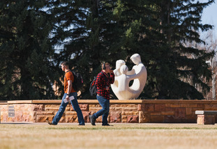 student walk by the universal family statue in pexys