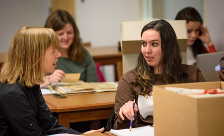 A student and UW staff member have an AHC archive file in front of them as they discuss one of the primary resources.