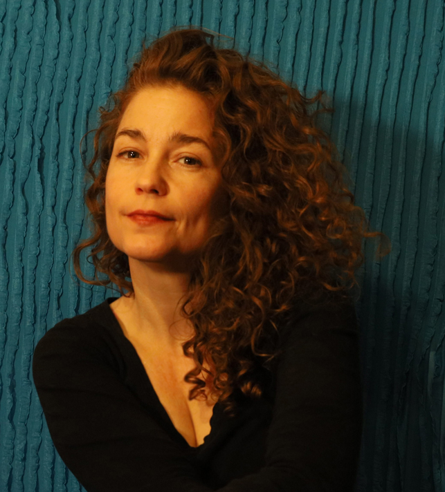 Smirking person in black with a blue textured background