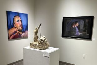 Art gallery with a statue in between two portraits.