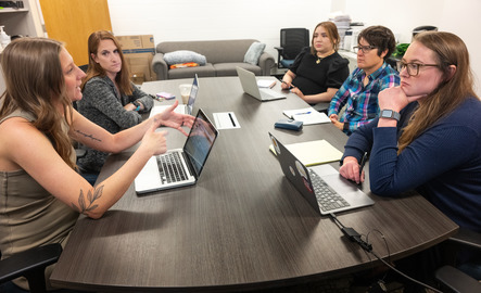 A group of UW students sit around a table and have a discussion