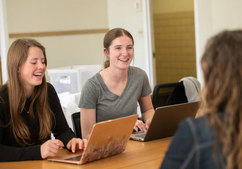 a student and advisor look at a computer screen