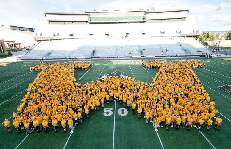A group of UW students in a W formation on the football field.