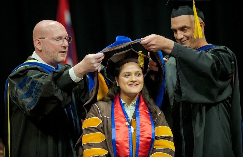 A doctoral student being hooded during commencement