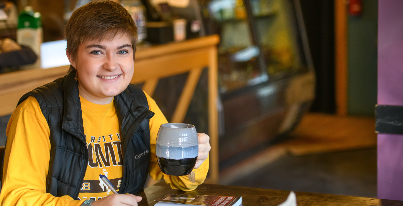 A UW student enjoys a coffee and works on coursework at a cafe near the University of Wyoming campus.