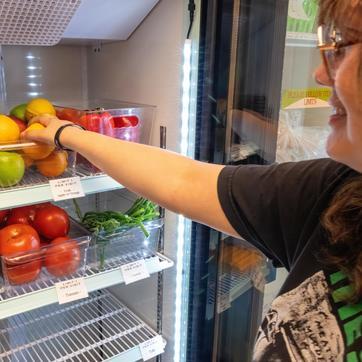 Student picking out produce from a refrigerator at the food pantry