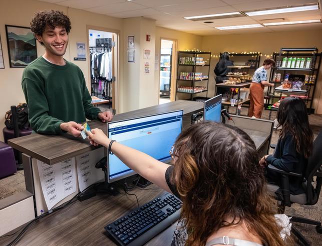 Student checking out at the PCCR desk with the pantry and closet in the background