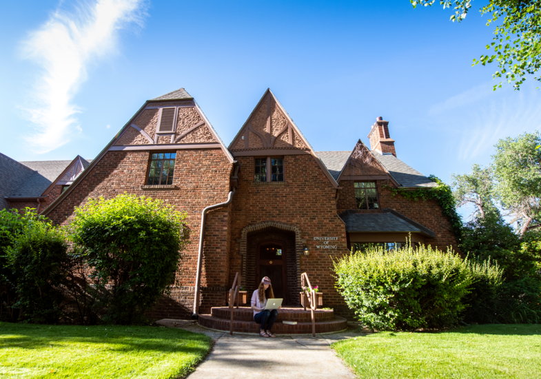 student sitting in front of the honors house