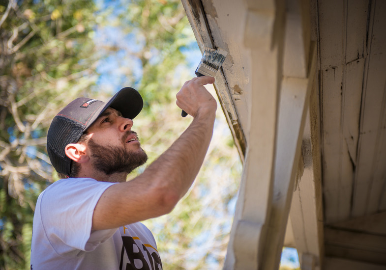 A UW fraternity member paints a house as part of a community service project
