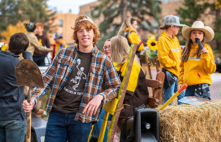 A UW Honors student stands with a shovel in hand surrounded by other individuals.