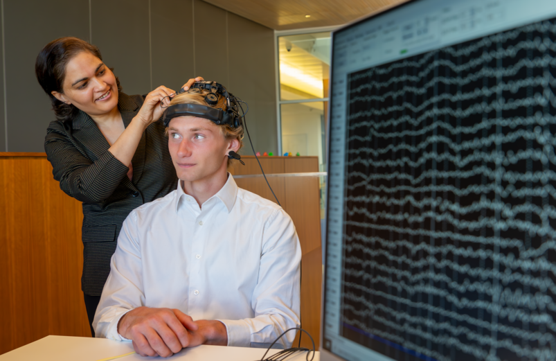 Diksha Shukla attaches a brain monitoring device to Zachary Nelson, a junior in Electrical Engineering who has participated in the lab studies and now interns in the lab.