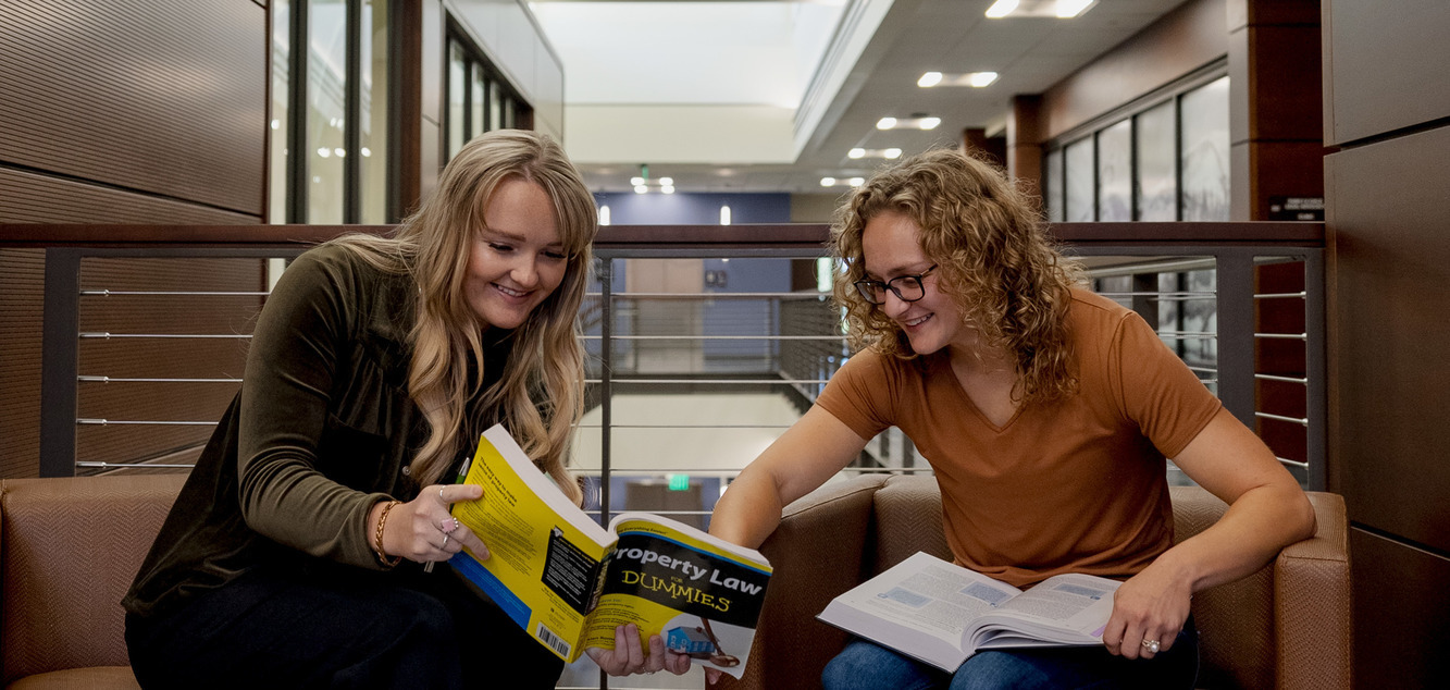 two students share a book in the law library