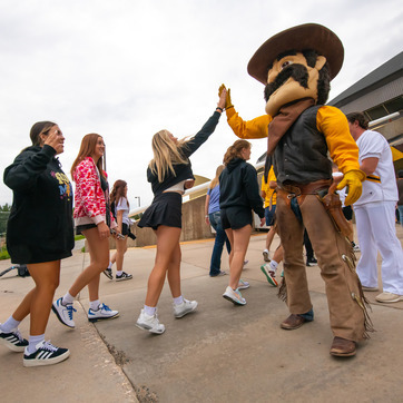 Student giving high fives to Pistol Pete