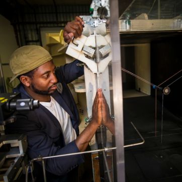 candid photo of a mechanical engineering student working on an expirement in a wind tunnel