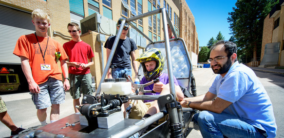 A group of students and a professor work on a cart together