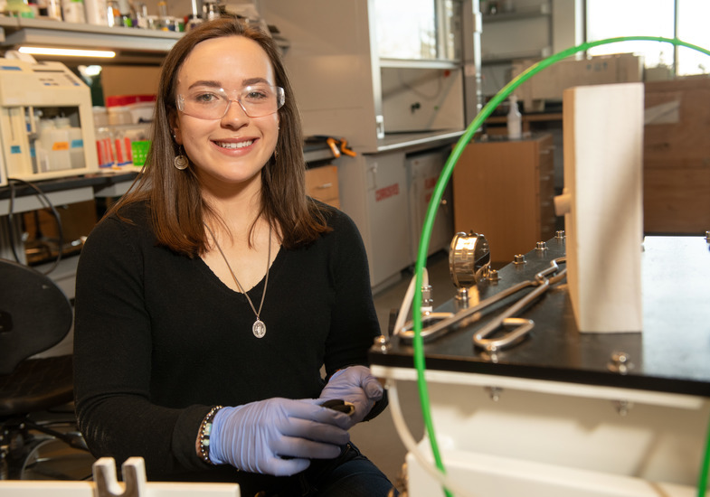 A mechanical engineering student smiles for a photo in a lab