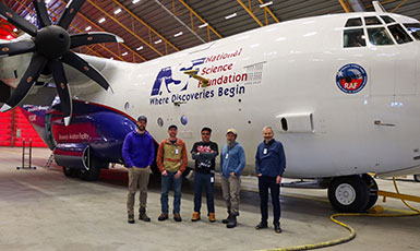 five people standing in front of a plane