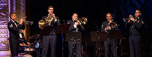 five people in uniforms playing brass instruments