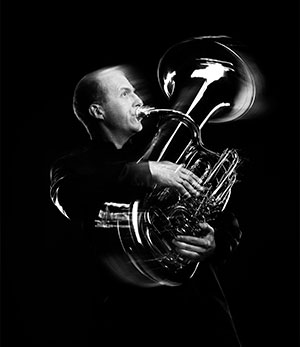 black and white photo of a man playing a tuba
