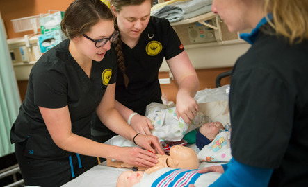 Students in the UW nursing school practice taking vitals from a simulator infant.