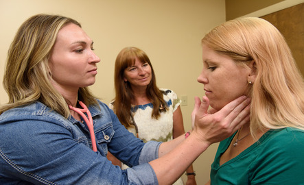 A UW student in the Fay W. Whitney School of Nursing works with a patient checking their lymph nodes as a mentor looks on for support.
