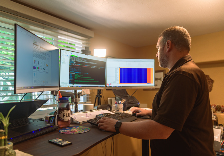 A UW faculty member works utilizing three computer monitors.