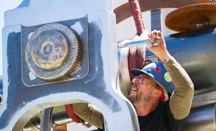 A UW community member uses a wrench to tighten part of a public art installation.
