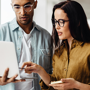 Two professionals standing and talking at a laptop