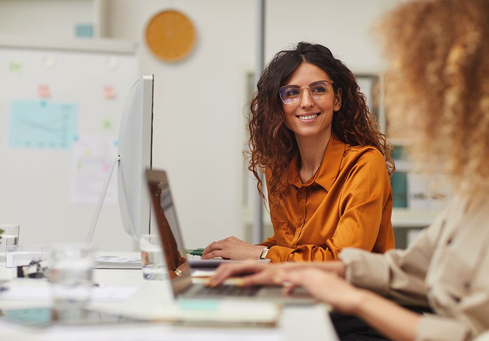 Two women smiling and working at computers