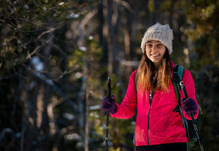 A student smiles for a photo while cross country skiing