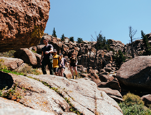 Four students hike on rocks at Vedauwoo