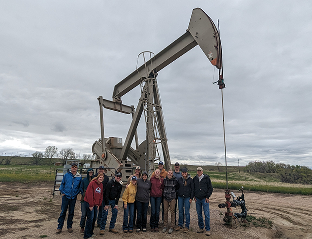 Students in the field standing in front of a pumpjack