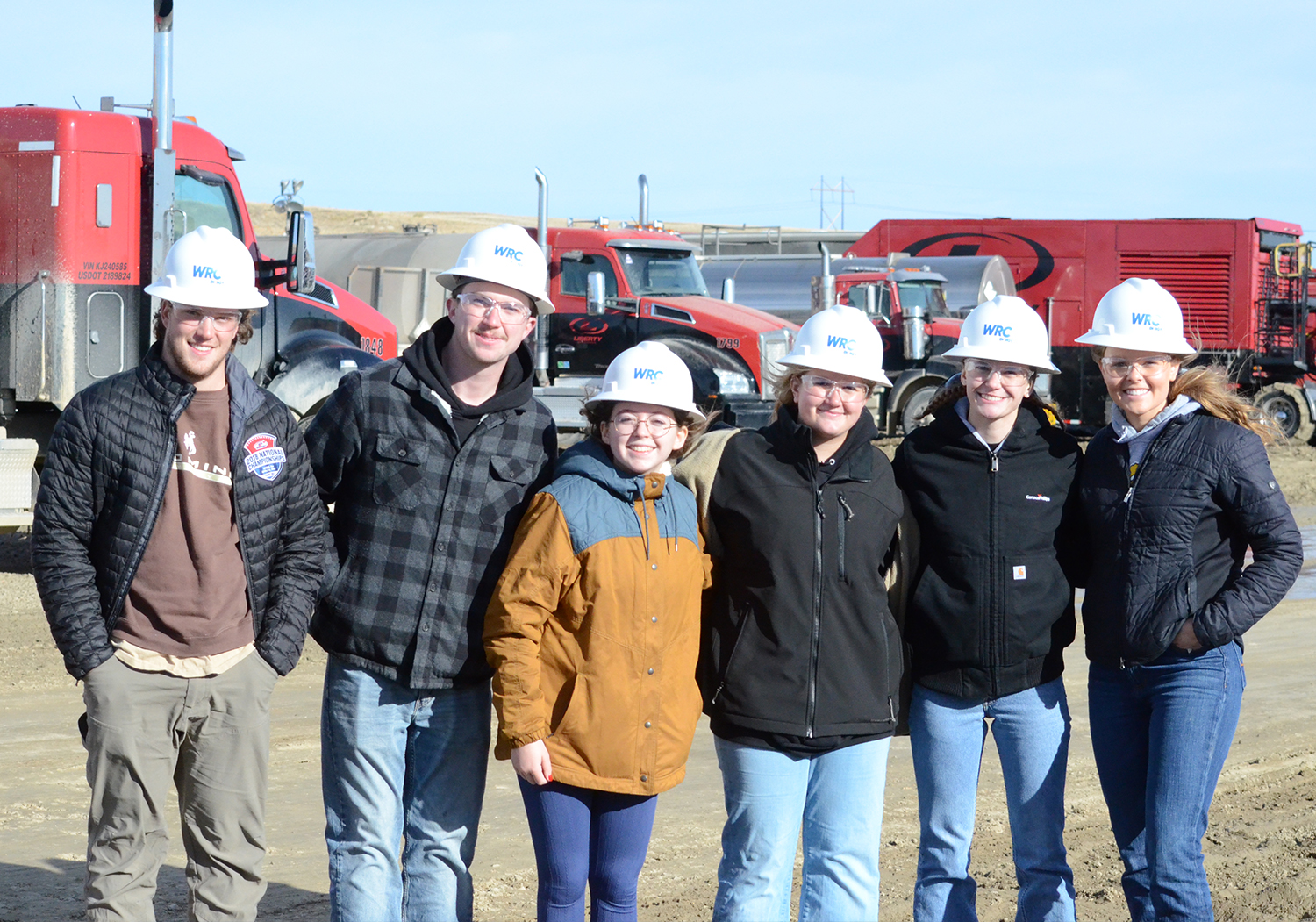 students at a frac site wearing hard hats on a field course