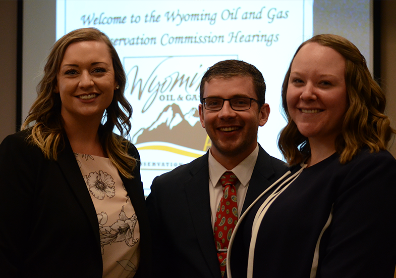 Students standing in front of a screen that says welcome to the Wyoming Oil and Gas Conservation Commission hearings