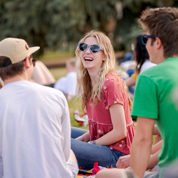 Three students laugh while sitting in the grass on Prexy's Pasture