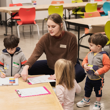 A teacher sits at a school table with three children