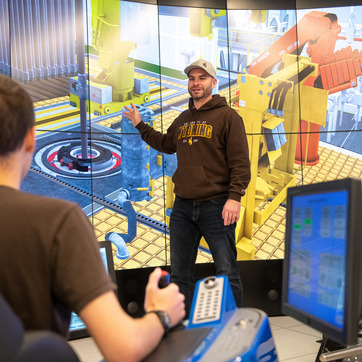 A student teaching another student on the drill simulator