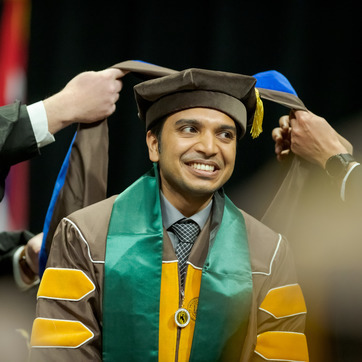 A Ph.D. student being hooded during commencement