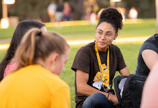A group of UW students sit together outside on the University of Wyoming campus.