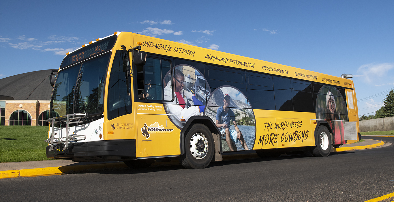 A UW shuttle is parked in front of a University of Wyoming building.
