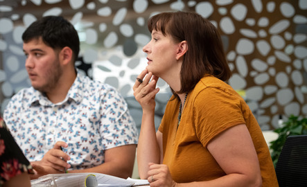 A student and faculty member listen to others speak