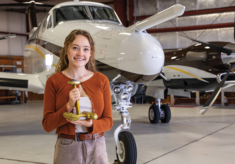female student holding a statue with airplane in background