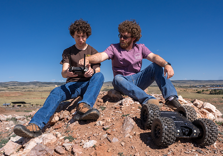 two people sitting on a rock with a robot