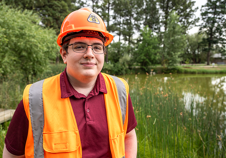person by a lake wearing a safety vest and hard hat
