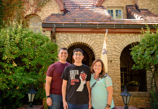 Parents and a UW student smile in front of a building on the University of Wyoming campus.